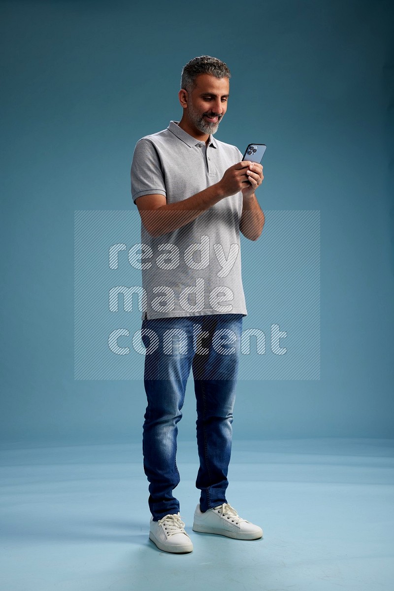 Man Standing texting on phone on blue background