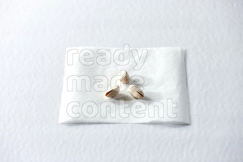 3 pistachios on a piece of paper on a white background in different angles