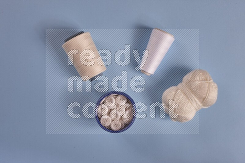 مجموعة من أدوات الخياطة والتفصيل بيضاء اللون على خلفية زرقاء