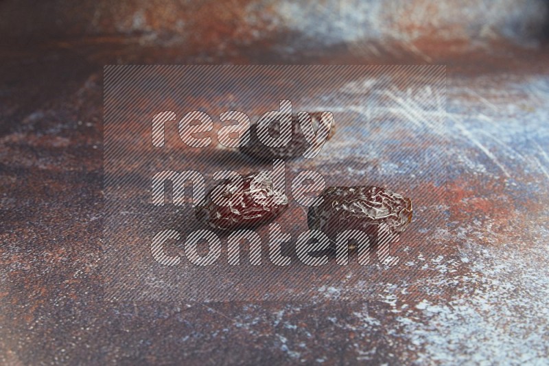 three madjoul dates on a rustic reddish background