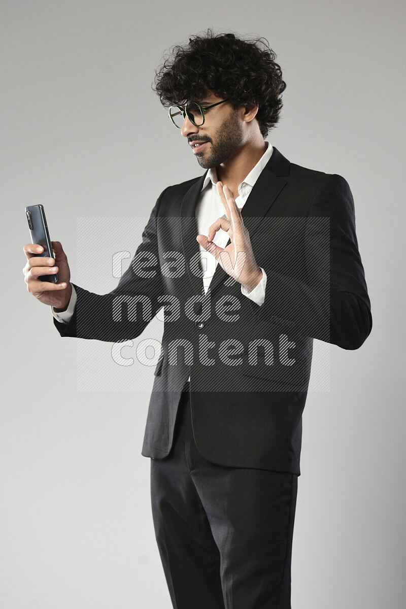 A man wearing formal standing and shooting with his phone on white background
