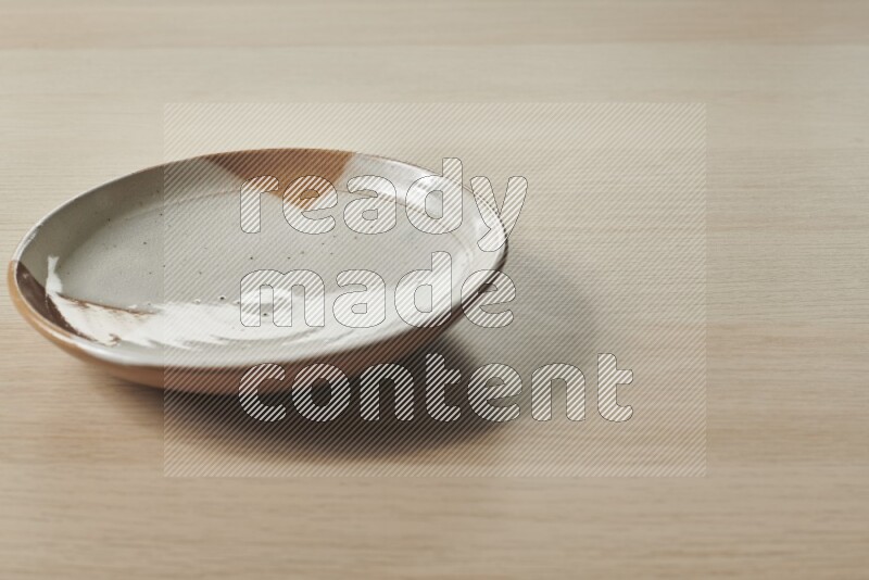 A multicolored pottery plate on light wooden background