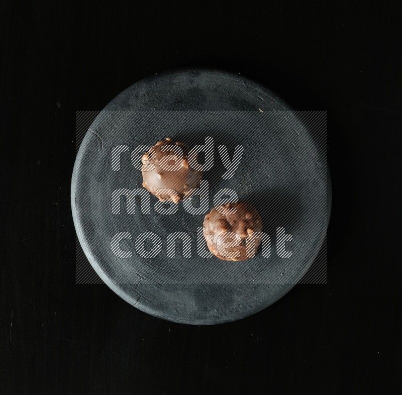 Assorted desserts in a black pottery plate on black background