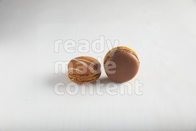 45º Shot of of two assorted Brown Irish Cream, and Yellow, and Brown Chai Latte macarons on white background