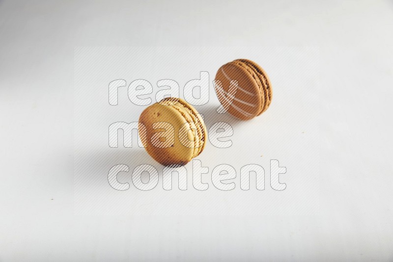 45º Shot of of two assorted Brown Irish Cream, and Yellow Crème Brulée macarons on white background