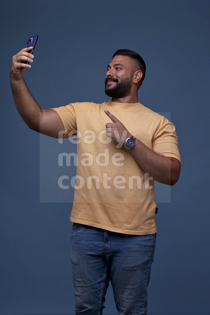 A man Taking A Selfie on Blue Background wearing Orange T-shirt