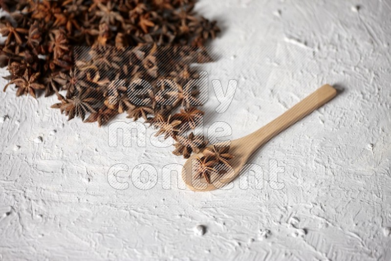 Star anise on a wooden spoon and spreading on the background on a white flooring