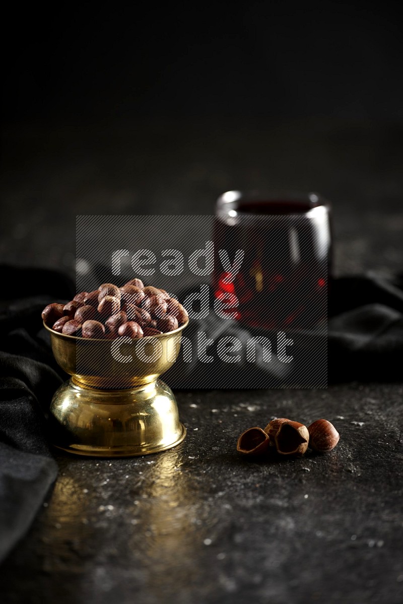 Nuts in a metal bowl with hibiscus and a napkin in a dark setup