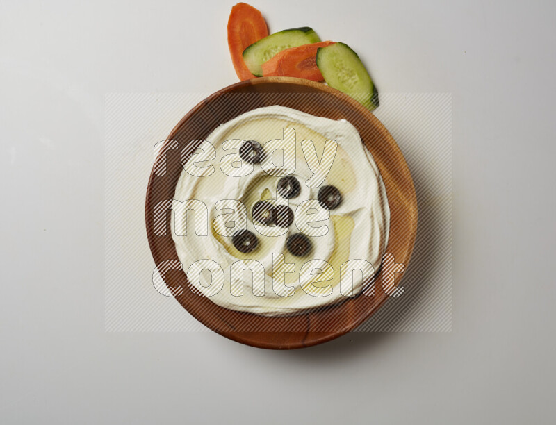 Lebnah garnished with sliced olives in a wooden plate on a white background
