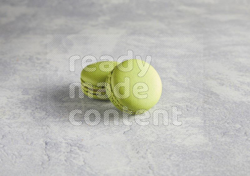 45º Shot of two Green Pistachio macarons  on white  marble background