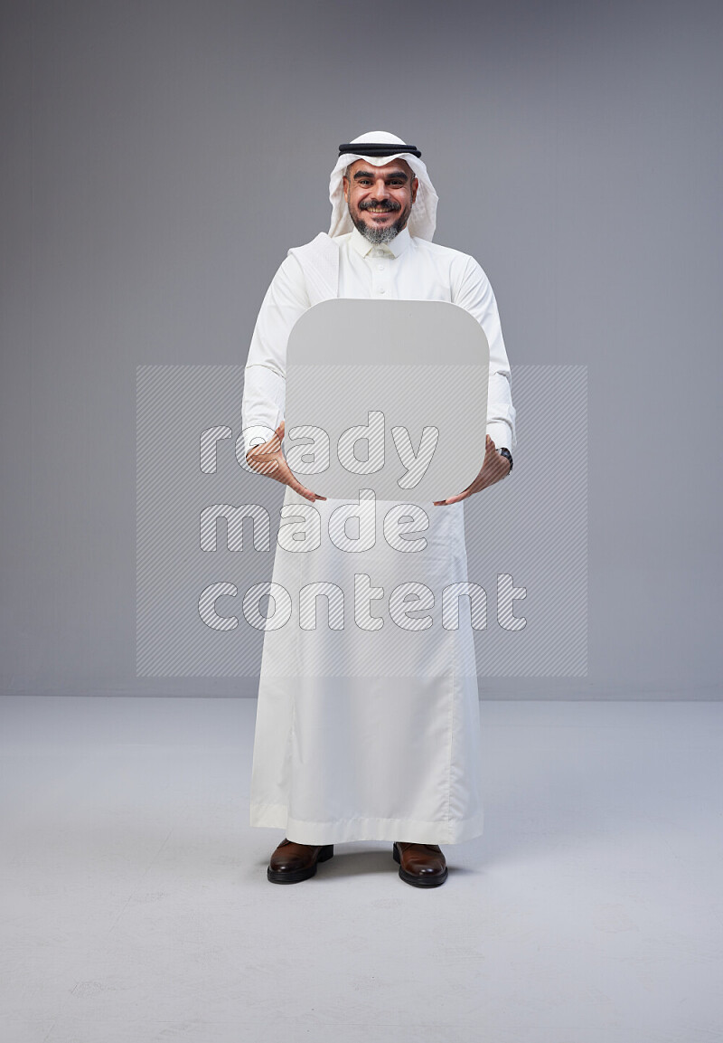 Saudi man Wearing Thob and white Shomag standing holding social media sign on Gray background