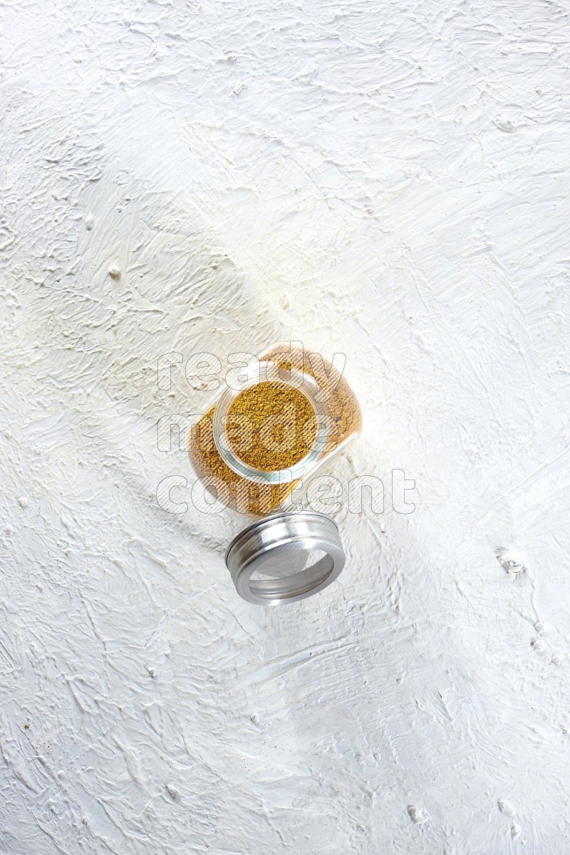 وعاء زجاجي للتوابل ممتلئ ببودرة الكركم على خلفية بيضاء