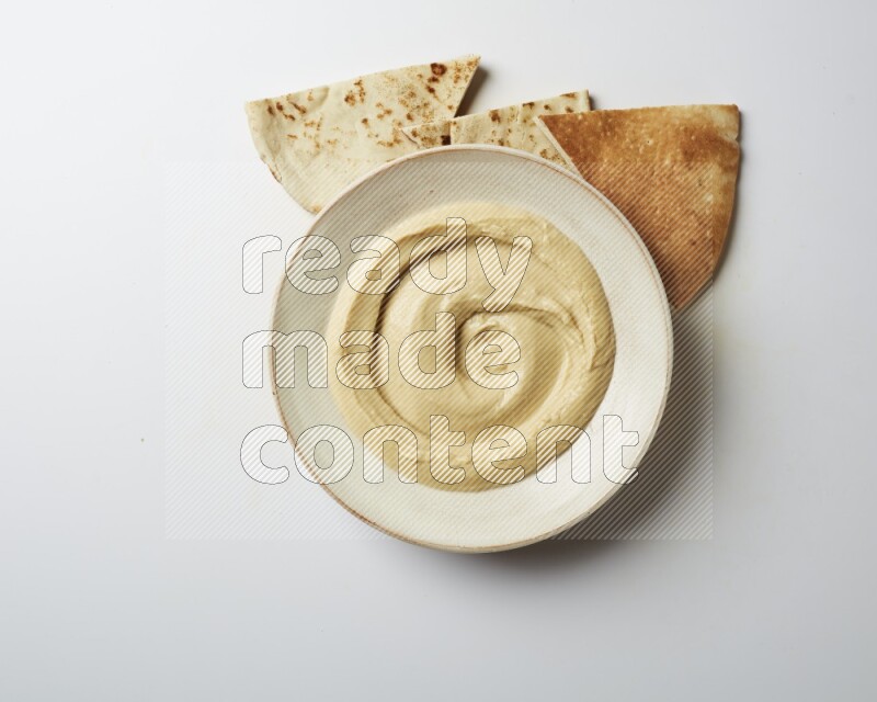 plain Hummus in a pottry plate  on a white background