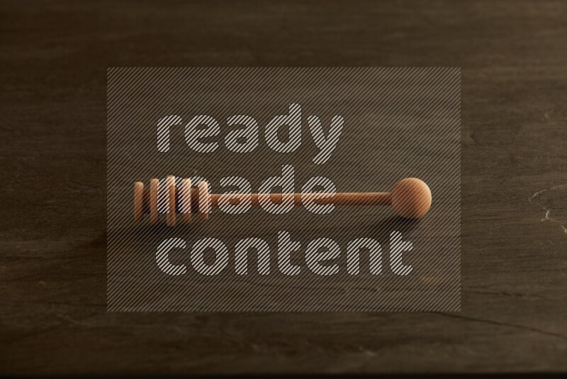 Wooden honey dipper on black slate background