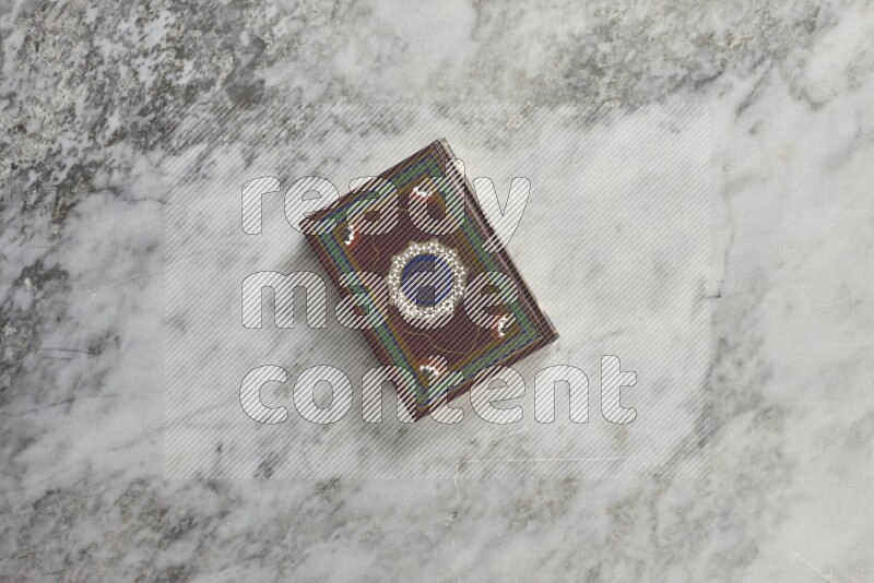 Quran with a prayer beads on grey marble background