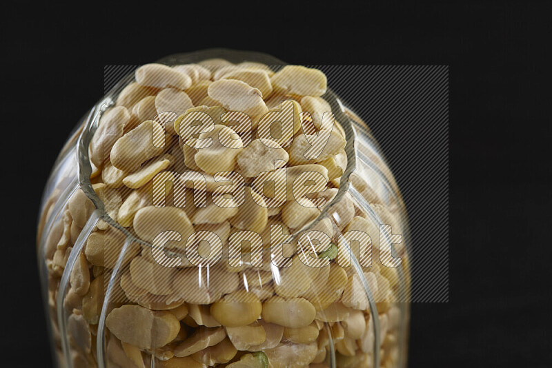 Crushed beans in a glass jar on black background