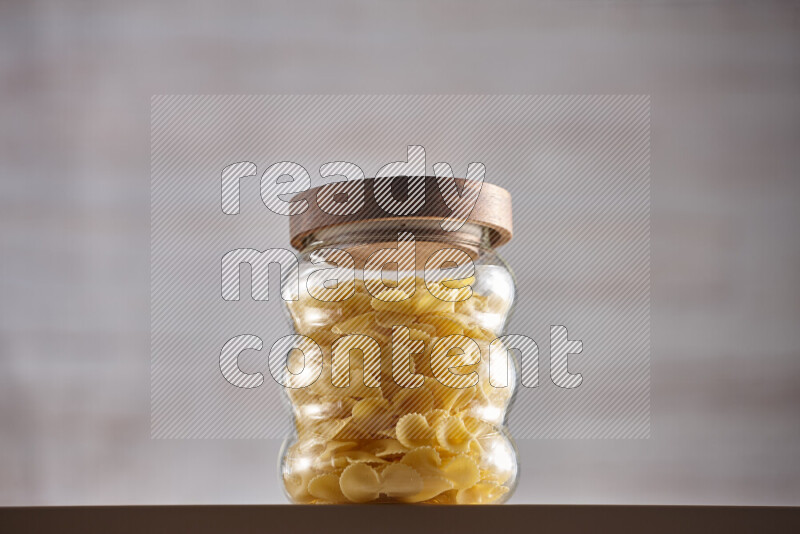 Raw pasta in glass jars on beige background