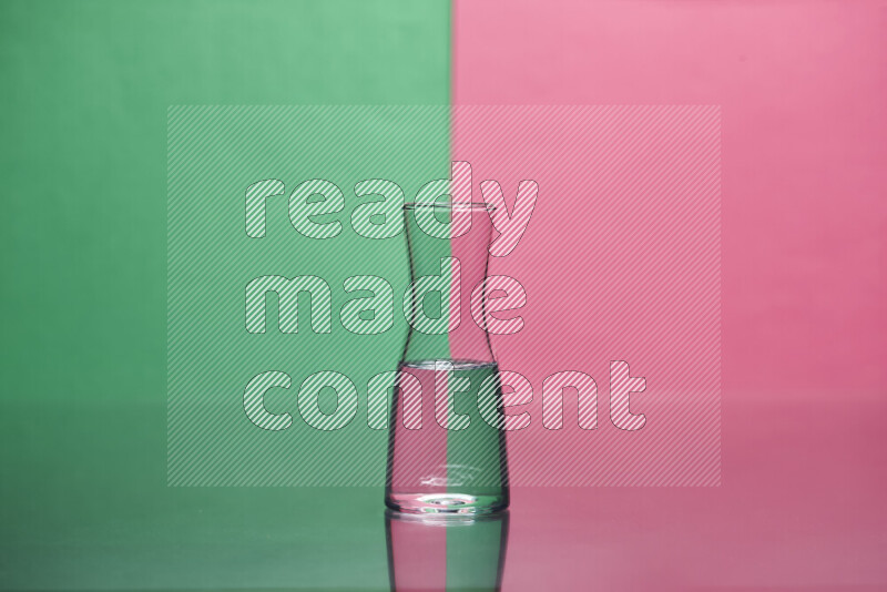 The image features a clear glassware filled with water, set against green and pink background