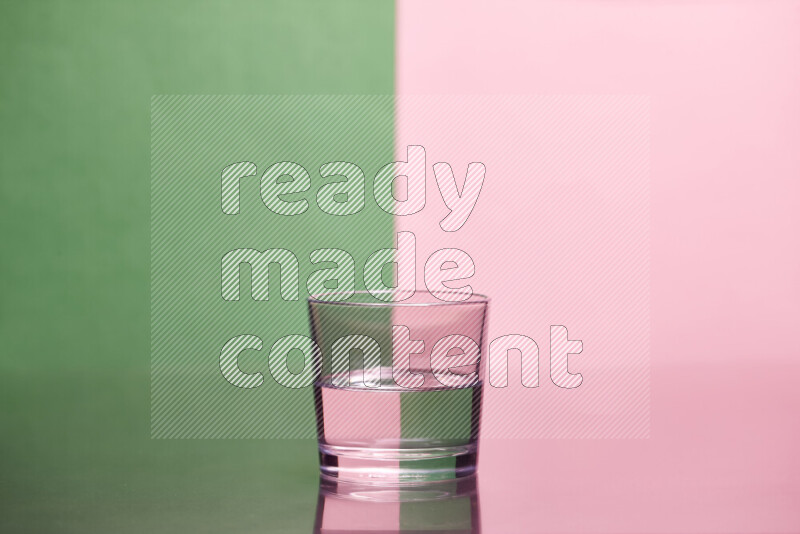 The image features a clear glassware filled with water, set against green and rose background