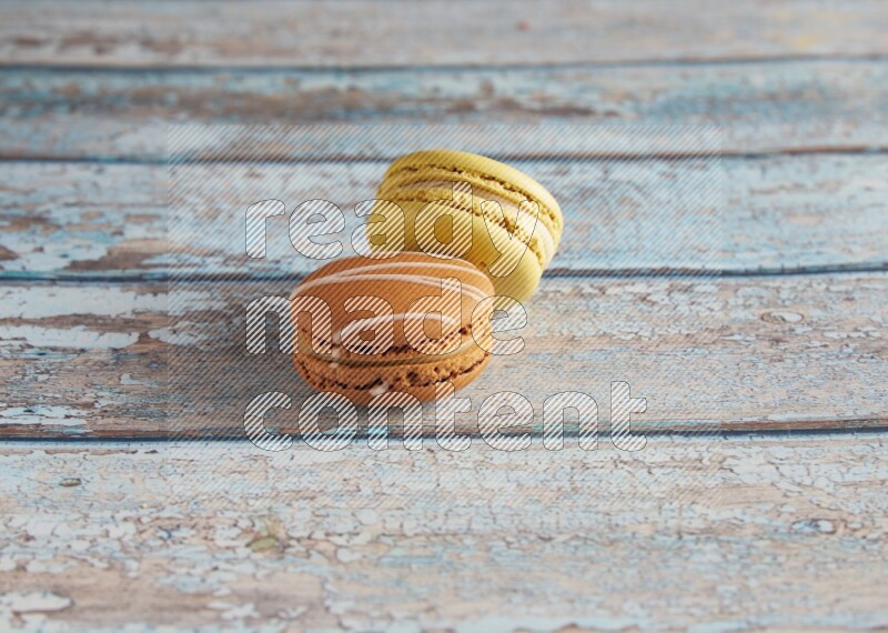 45º Shot of of two assorted Brown Irish Cream, and Yellow Lime macarons on light blue background