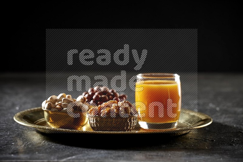 Nuts in metal bowls with qamar eldin on a tray in dark setup