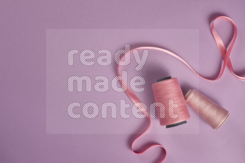 A pink and purple collection of sewing and tailoring tools arranged on a purple background