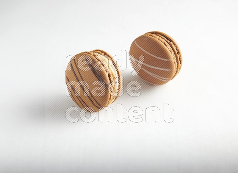 45º Shot of of two assorted Brown Irish Cream, and light brown  Almond Cream macarons on white background
