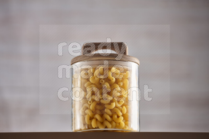 Raw pasta in glass jars on beige background
