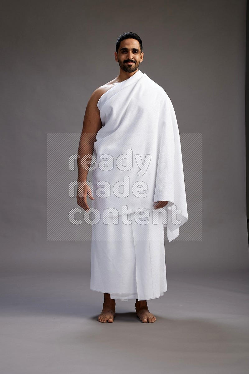 A man wearing Ehram Standing Interacting with the camera on gray background