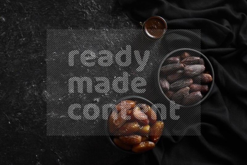 تمر في أوعية فخارية مع القهوة علي خلفية سوداء خشبية