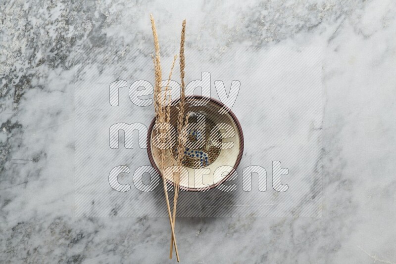 Wheat stalks on decorative pottery plate on grey marble background