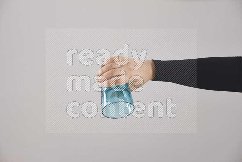 A woman in black abaya holding different glassware in different positions