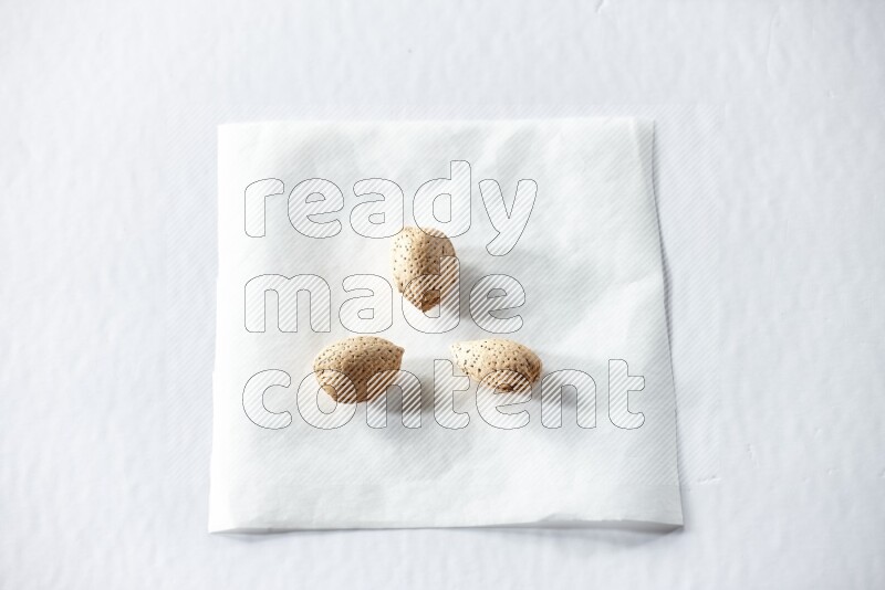 3 almonds on a piece of paper on a white background in different angles