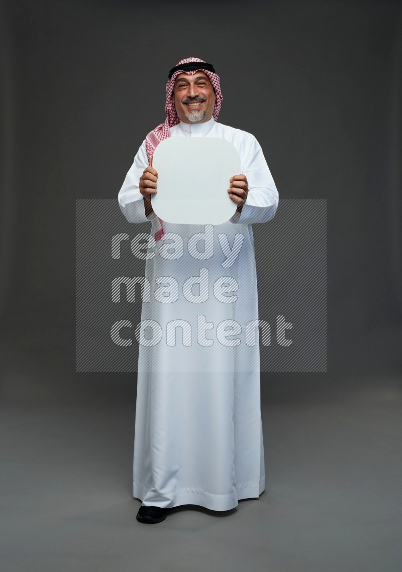 Saudi man with shomag Standing holding social media sing on gray background