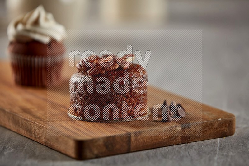 Chocolate cupcake topped with pecan on a wooden board