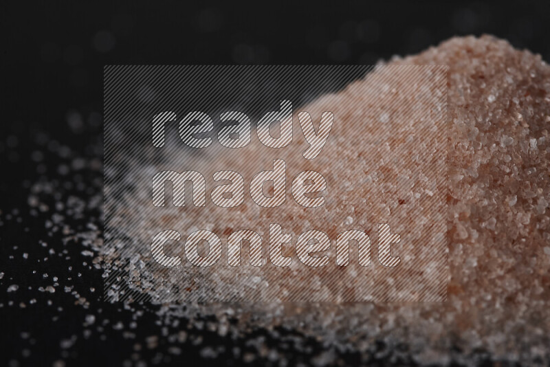 A bunch of fine himalayan pink salt on black background