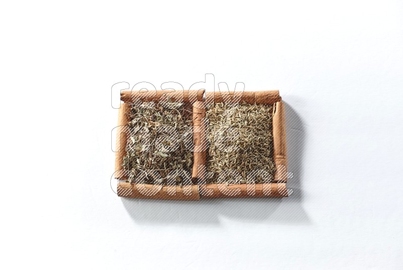 2 squares of cinnamon sticks full of dried basil and cumin on white flooring