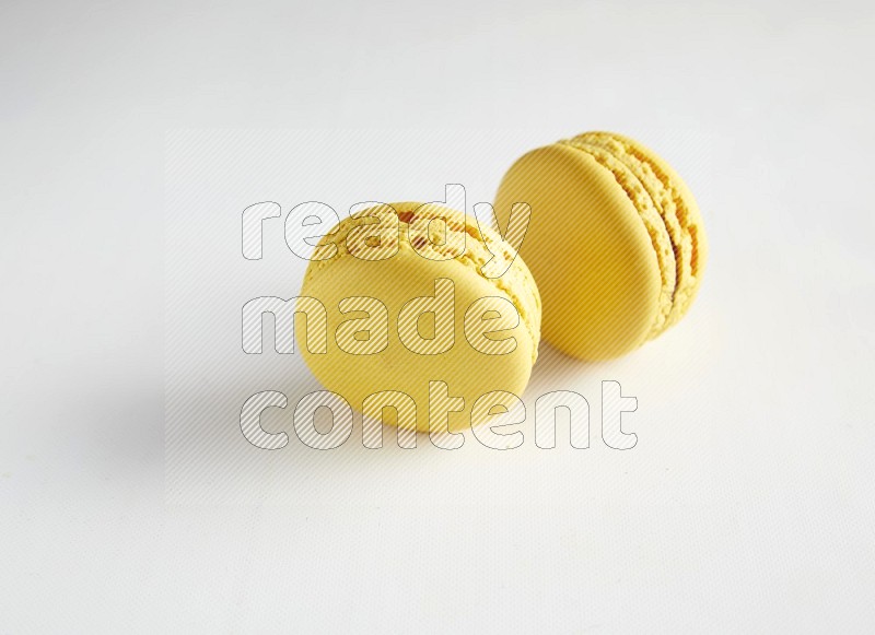 45º Shot of two Yellow Lemon macarons on white background