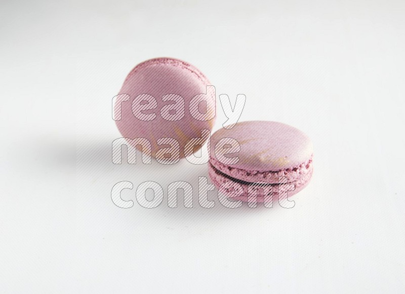 45º Shot of two Purple Strawberry macarons on white background