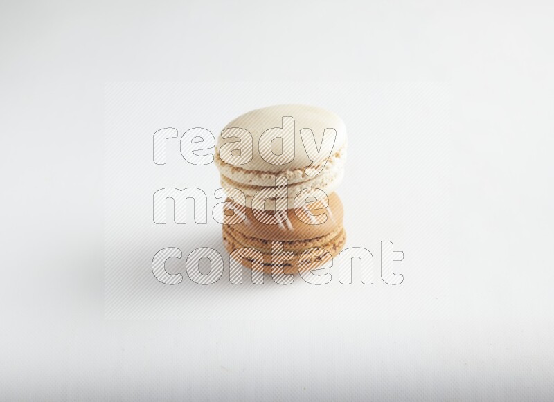 45º Shot of of two assorted Brown Irish Cream, and White Caramel fleur de sel macarons on white background