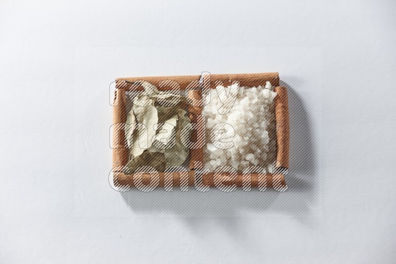 2 squares of cinnamon sticks full of white salt and laurel bay leaves on white flooring