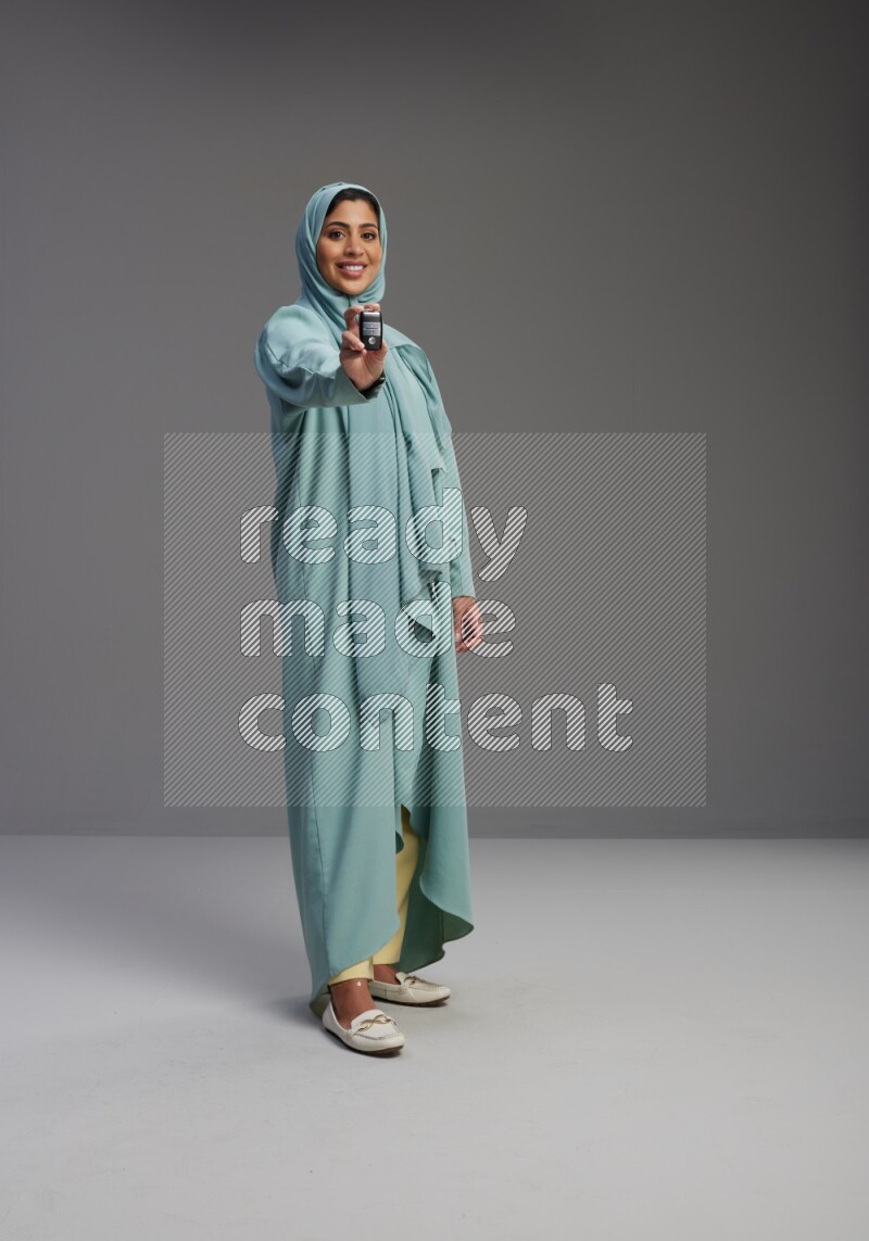 Saudi Woman wearing Abaya standing holding car key on Gray background