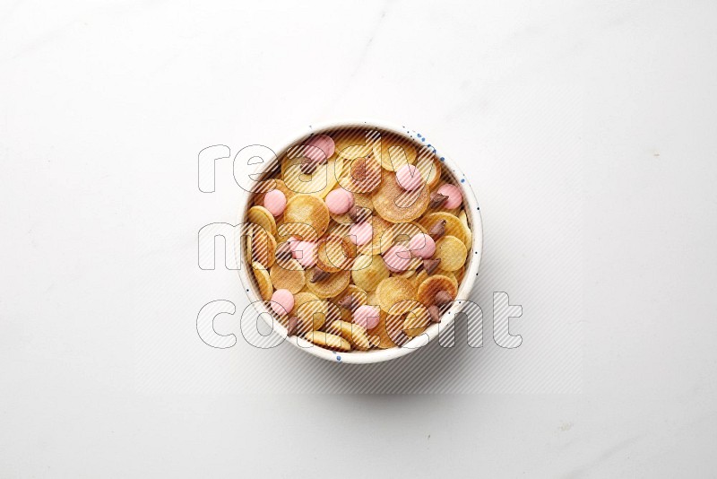Top-view shot of mixed chocolate chips cereal pancakes in a round bowl on white background