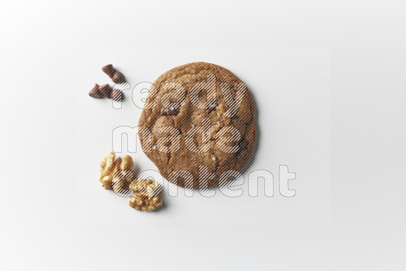 A single chocolate chips cookie with chocolate and walnuts beside it on a white background