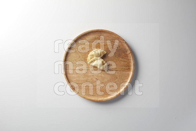 Two Sambosas on a wooden round plate on a white background