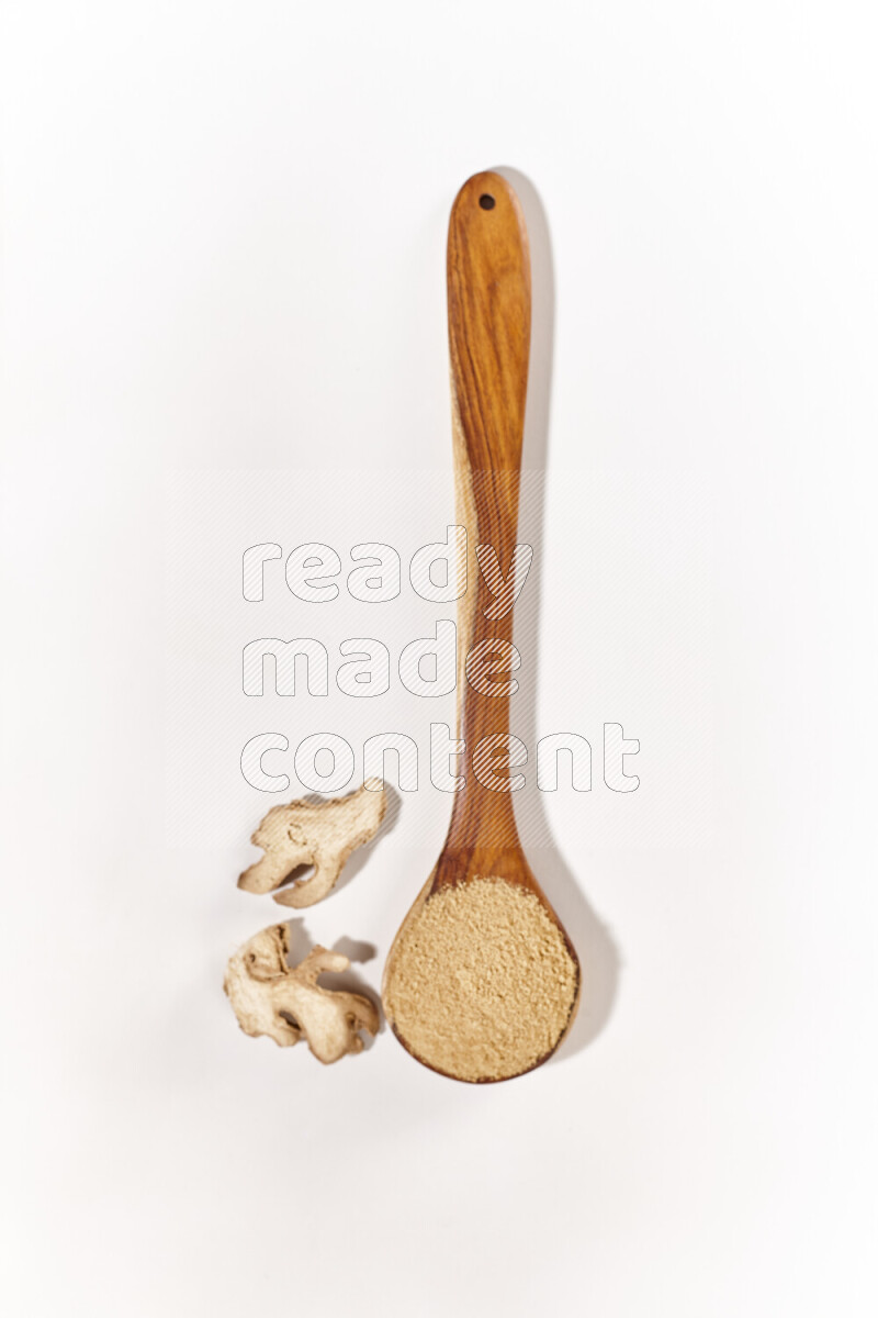 A wooden ladle full of ground ginger powder on white background