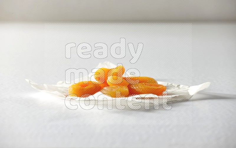 Dried apricots on a crumpled piece of paper on a white background in different angles