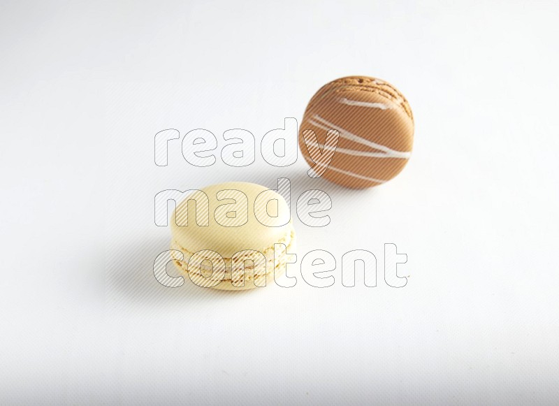 45º Shot of of two assorted Brown Irish Cream, and Yellow Vanilla macarons on white background