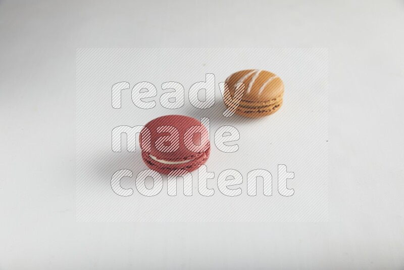 45º Shot of of two assorted Brown Irish Cream, and Red Velvet macarons on white background
