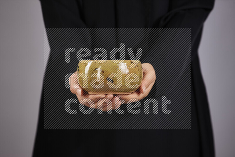 A woman in black abaya holding different pottery essentials in different positions